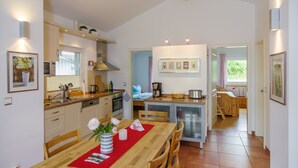 A modern kitchen with wooden cabinets, a dining table with chairs, and a red placemat.