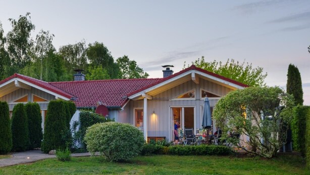 A two-story house with a red-tiled roof, a covered porch, and a well-maintained lawn.
