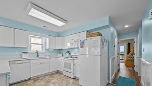 A modern kitchen with white cabinets, a built-in oven, a refrigerator, and a microwave. - A Sassy Siren - 3BR Townhouse on Topsail Island with Ocean and Sound Views (North Topsail Beach)
