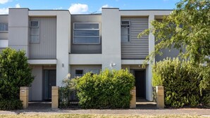 A modern multi-story residential building with a symmetrical facade, large windows, and a well-maintained lawn. - The Charming Living 3BR Townhouse/Perfect Vacation (Largs North)