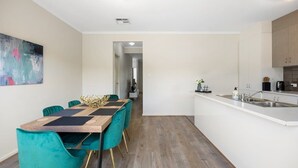 A modern kitchen with a central island, teal chairs, and a wooden dining table. - The Charming Living 3BR Townhouse/Perfect Vacation (Largs North)