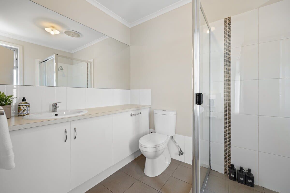 A modern bathroom with a glass shower enclosure, a white toilet, and a beige countertop.