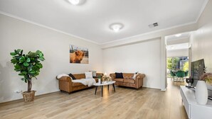 A modern living room with two sofas, a coffee table, and a large plant. - The Charming Living 3BR Townhouse/Perfect Vacation (Largs North)