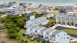 Ein Küstenwohngebiet mit mehrstöckigen Häusern, einem Strand im Hintergrund und einer klaren Straße, die zum Strand führt.