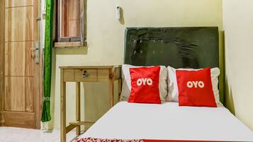 A bedroom with a bed, a wooden wardrobe, a small table, and a green curtain.