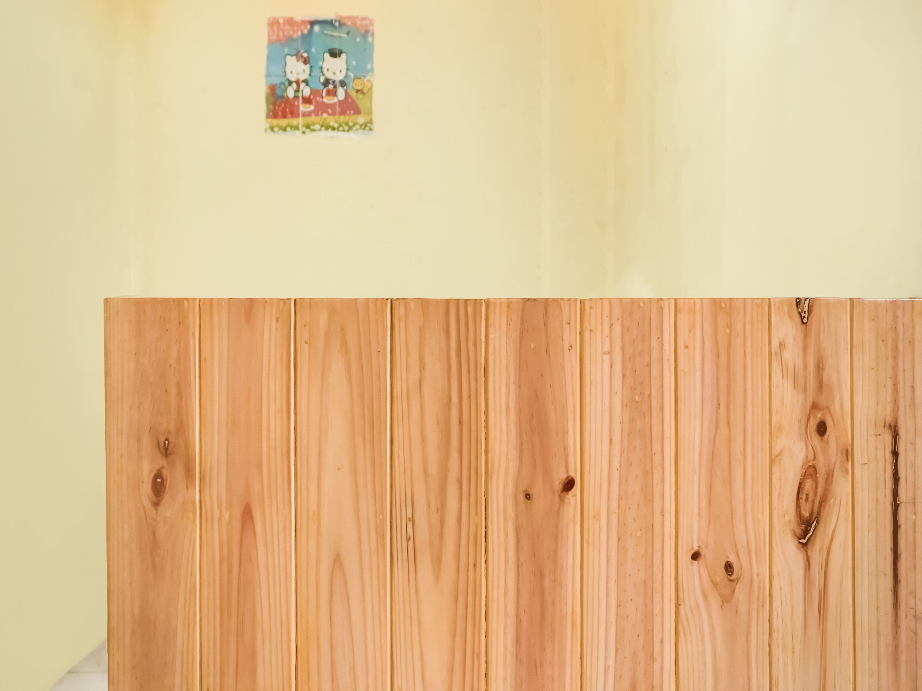 A wooden panel wall with a Hello Kitty sticker.