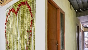 A hallway with a door, a sign reading "SPOT ON", and a decorative curtain with red flowers. - OYO Life 91335 Micheline Family 2 Syariah (Karawang)