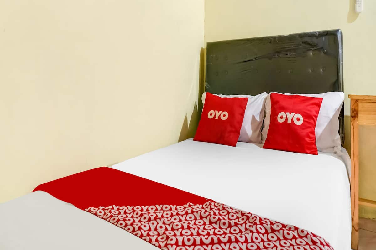 Una cama con colcha y almohadas rojas y blancas, con la marca "OYO".