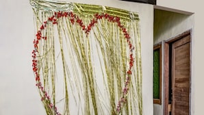 A wall with a heart-shaped decoration made of golden streamers and red flowers. - OYO Life 91335 Micheline Family 2 Syariah (Karawang)