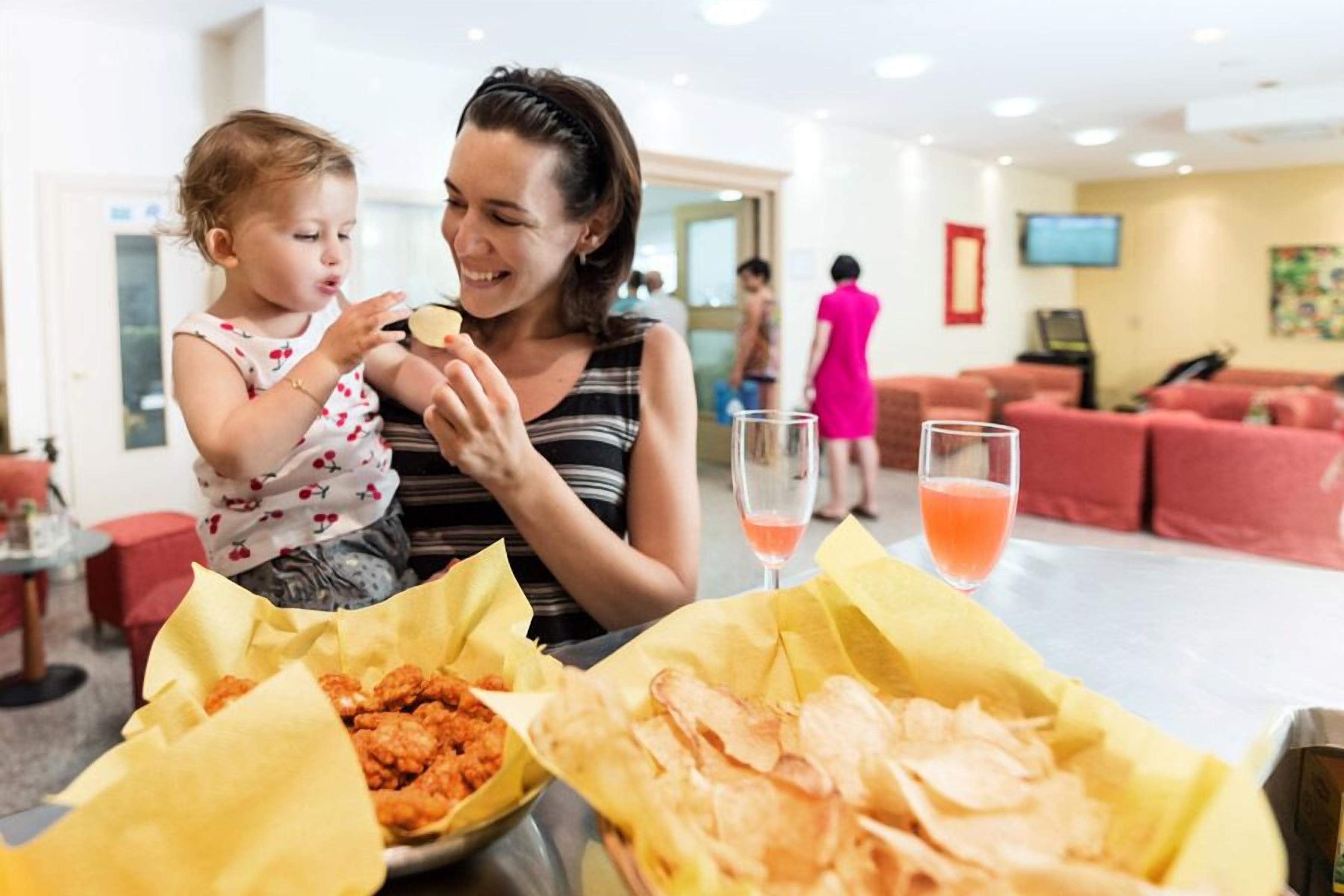 Uma mulher e uma criança jantando à mesa, com comida e bebida.