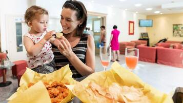 Uma mulher e uma criança jantando à mesa, com comida e bebida.