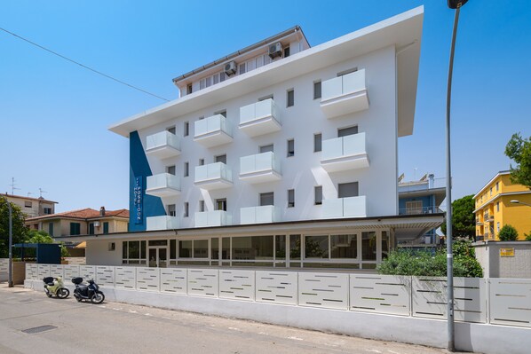 A modern building with multiple balconies, a covered entrance, and a row of windows along the ground floor. - Hotel Poseidon e Nettuno (San Benedetto del Tronto)