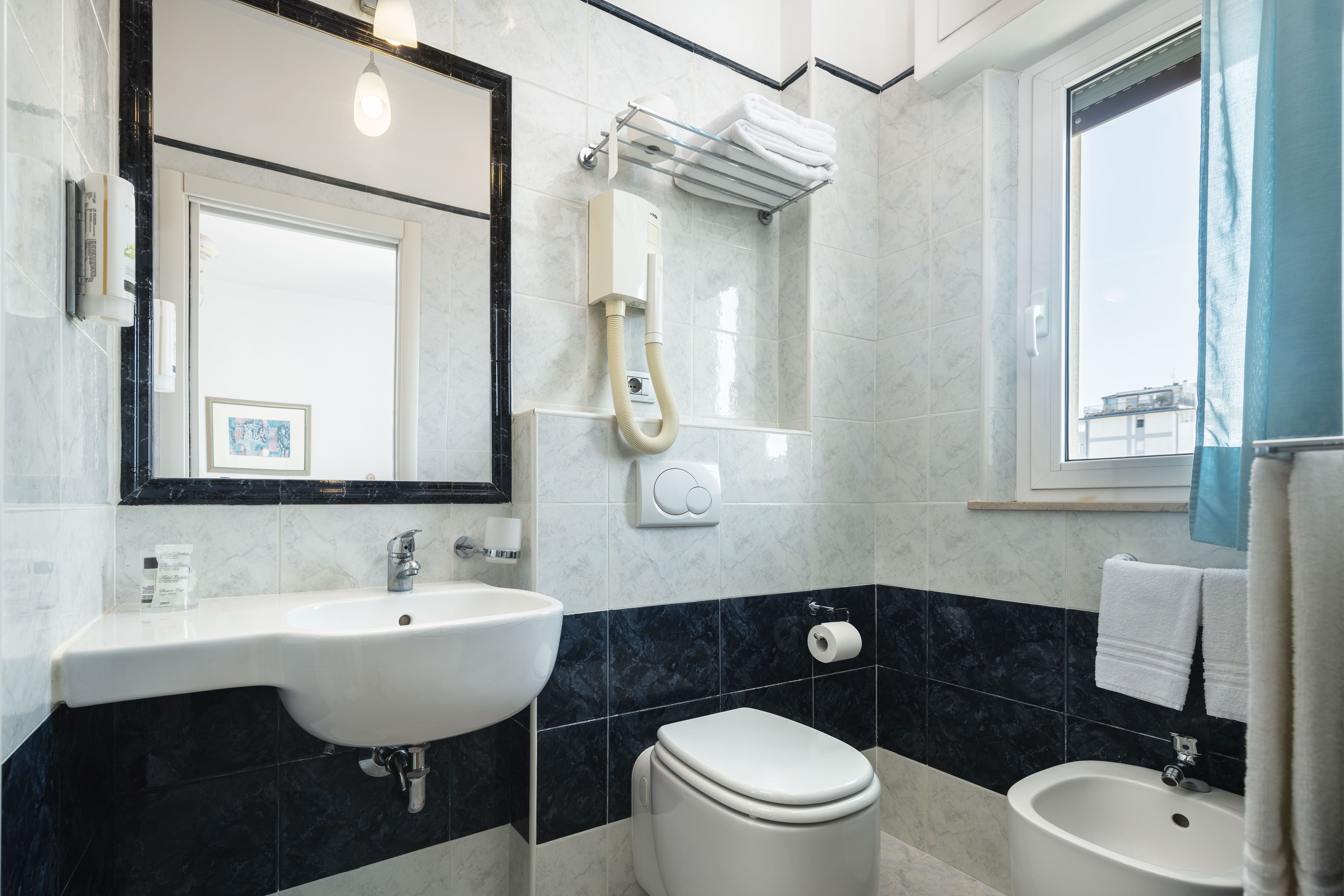 A modern bathroom with a sink, toilet, bidet, and a large mirror.