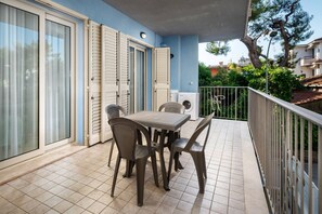 A balcony with a table and chairs, a washing machine, and a sliding glass door. - Hotel Poseidon e Nettuno (San Benedetto del Tronto)
