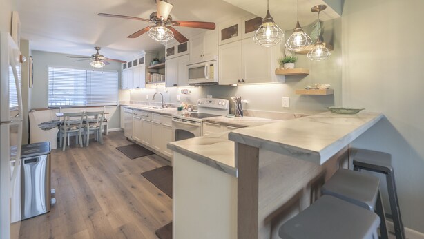 A modern kitchen with white cabinets, a central island, and pendant lighting. - Canal front Sanibel condo, short stroll to the Gulf of Mexico. (Sanibel)