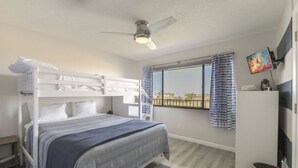 A bedroom with a bunk bed, a desk, a chair, a window with curtains, and a ceiling fan. - Canal front Sanibel condo, short stroll to the Gulf of Mexico. (Sanibel)