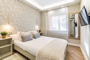 Relax in this serene bedroom with a large bed, nightstand, and potted plant, surrounded by a leaf-patterned wallpaper and a large mirror.