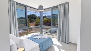 Camera da letto moderna con un'ampia finestra, un letto con lenzuola bianche e vista sull'esterno.