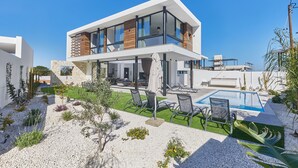 Una moderna casa a due piani con piscina, area relax esterna e giardino curato.