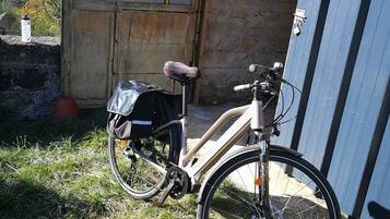 Een fiets geparkeerd voor een landelijk pand met een houten en een blauwe deur.