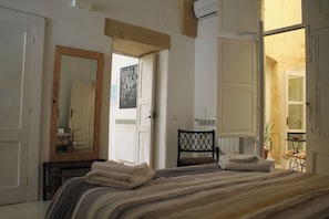 A bedroom with a bed, a mirror, a chair, and a door leading to a bathroom.