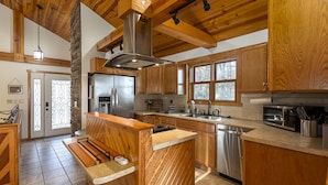 A kitchen with wooden cabinets, a stainless steel refrigerator, a built-in oven, and a large window.