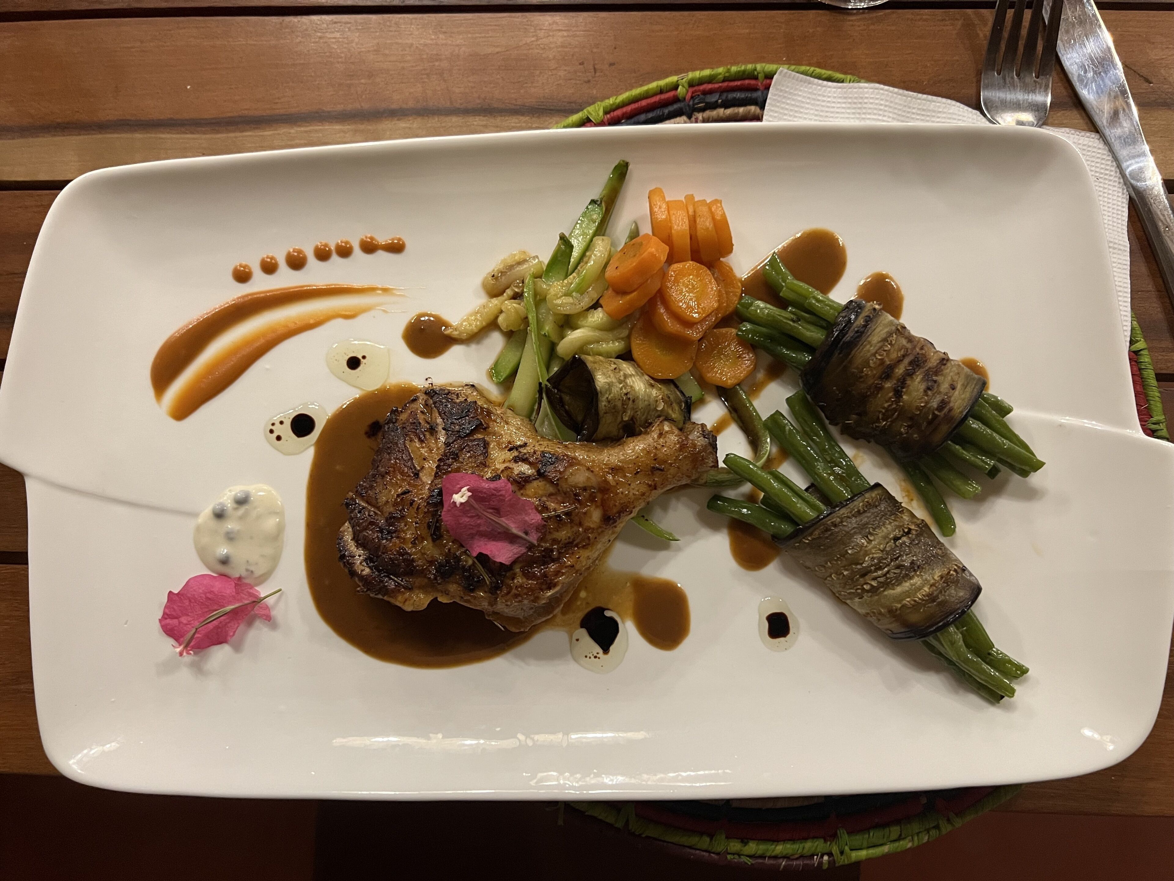 A white plate with a grilled meat, vegetables, and sauce.