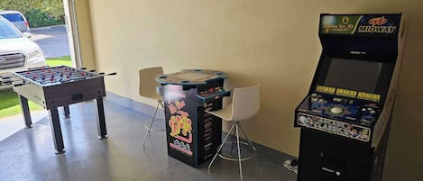 Un garaje con mesa de fútbol, máquina de golf arcade en 3D y una silla.