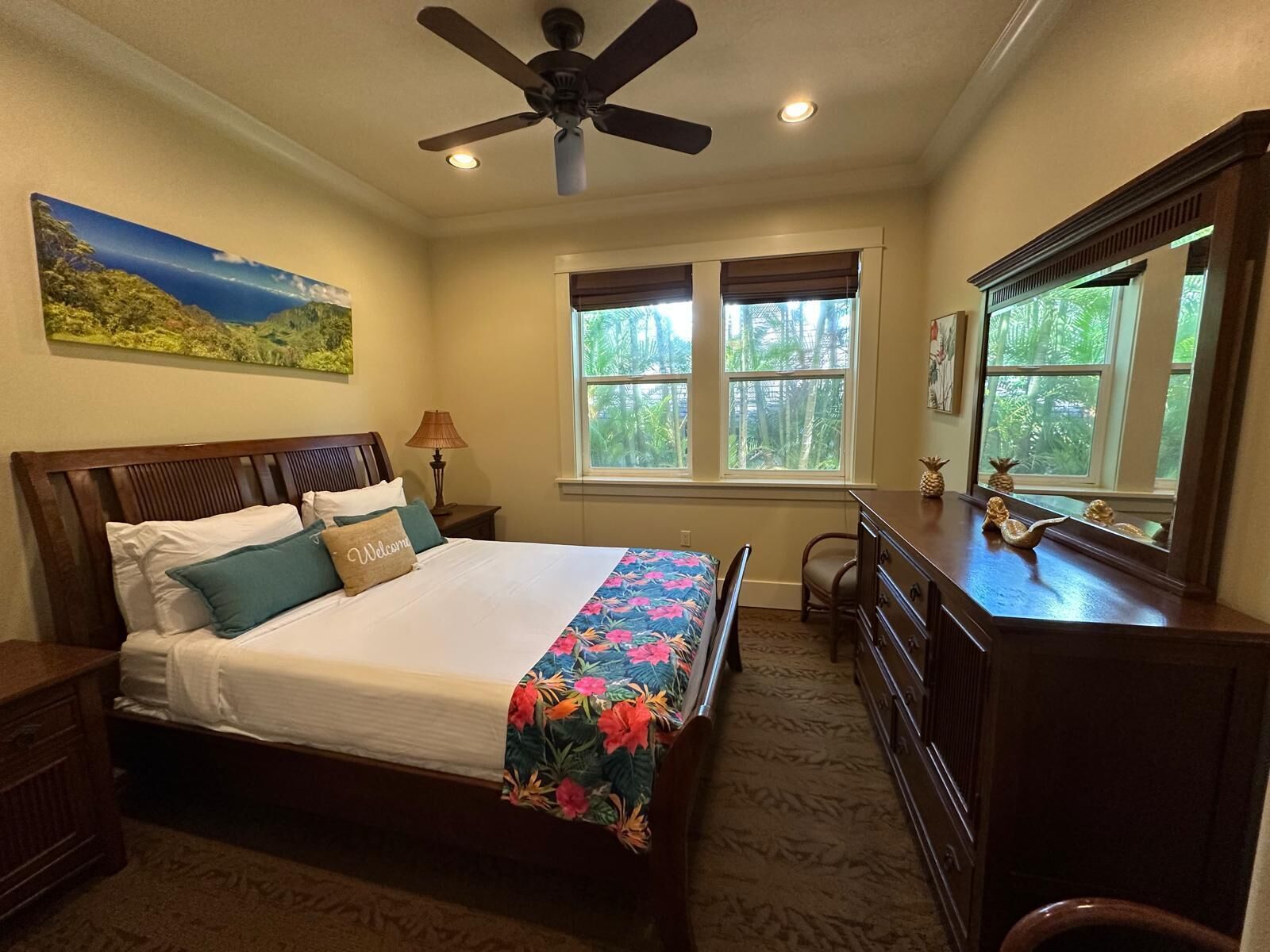 A bedroom with a bed, a desk, a chair, a ceiling fan, and a window with blinds.