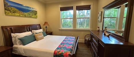A bedroom with a bed, a desk, a chair, a ceiling fan, and a window with blinds.