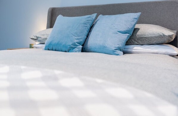 A neatly made bed with a grey headboard and two light blue pillows. - Rothbury Hideaway at the heart of the village (Rothbury)