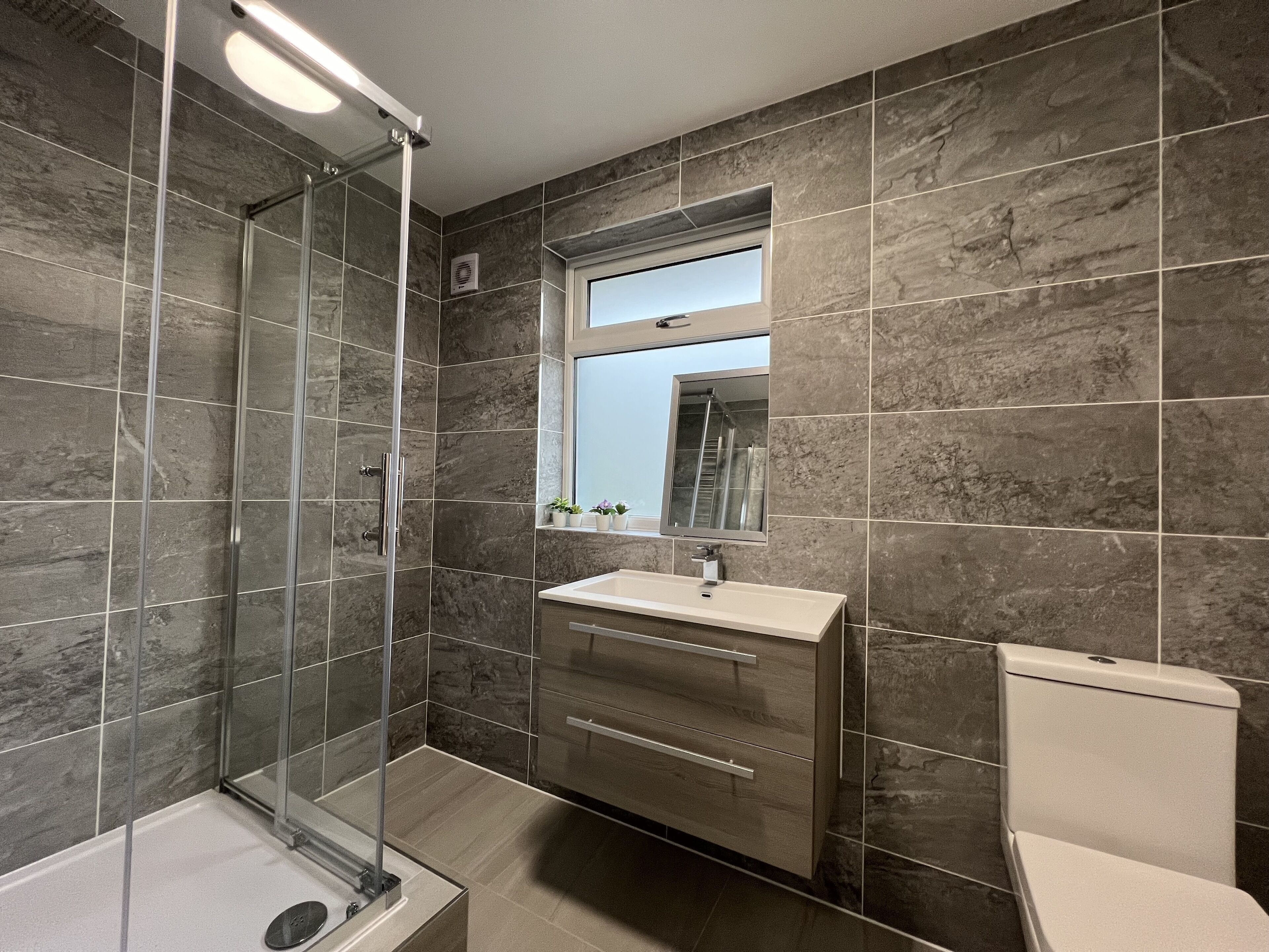 A modern bathroom with a glass shower enclosure, a vanity with a sink, and a toilet.