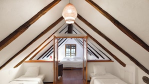 A bedroom with two beds, wooden beams, a hanging light fixture, and a window. - Rustico al platano 2 (Sonogno)