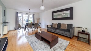 Ein modernes Wohnzimmer mit einem dunkelbraunen Couchtisch, einem grauen Sofa und einem großen Spiegel an der Wand.