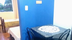 Een klein eetgedeelte met een tafel en stoelen, een blauwe muur met borden en uitzicht op de omgeving.