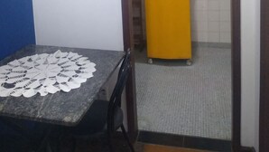 Een kleine keuken met houten kastjes, een gele koelkast en een betegelde achterwand.