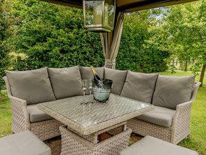 Relax in a serene outdoor setting with a wicker sofa and glass table, perfect for casual gatherings.