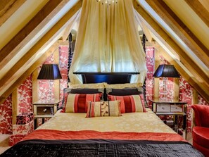 Cozy attic-style room with a large bed, bedside tables, and a comfortable chair.