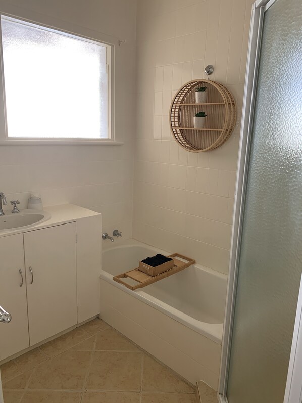 A bathroom with a bathtub, a sink, and a window. - Great central location, one street back from the beach. (Beresford)