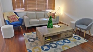Un salon avec un canapé, des fauteuils, une table basse et un petit sapin de Noël.
