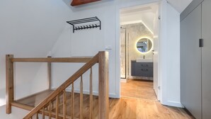 A wooden staircase leading to a bathroom with a round mirror and a sink. - MARGI Gran Apartament (Szczecin)