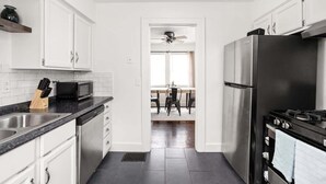 A modern kitchen with white cabinets, a stainless steel refrigerator, and a microwave. - Backyard+Porch, Pet-Friendly | Broad Ripple Stay (Indianapolis)