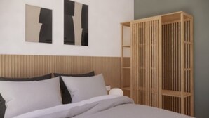 A bedroom with a bed, a wooden wardrobe, and abstract wall art. - Sea View Studio by Dominium (Dubrovnik)