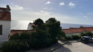 A coastal residential area with terracotta-roofed houses, a paved street, and a parked car. - Sea View Studio by Dominium (Dubrovnik)