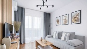 A modern living room with a grey sofa, wooden coffee table, and a TV on a wooden stand.