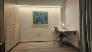 A room with a desk, chair, and a painting on the wall. - Nest By Rivido Apart Hotel (Bengaluru)