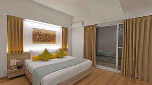 A modern hotel room with a large bed, a bedside table with a lamp, a painting on the wall, and a sliding glass door to the outside. - Nest By Rivido Apart Hotel (Bengaluru)