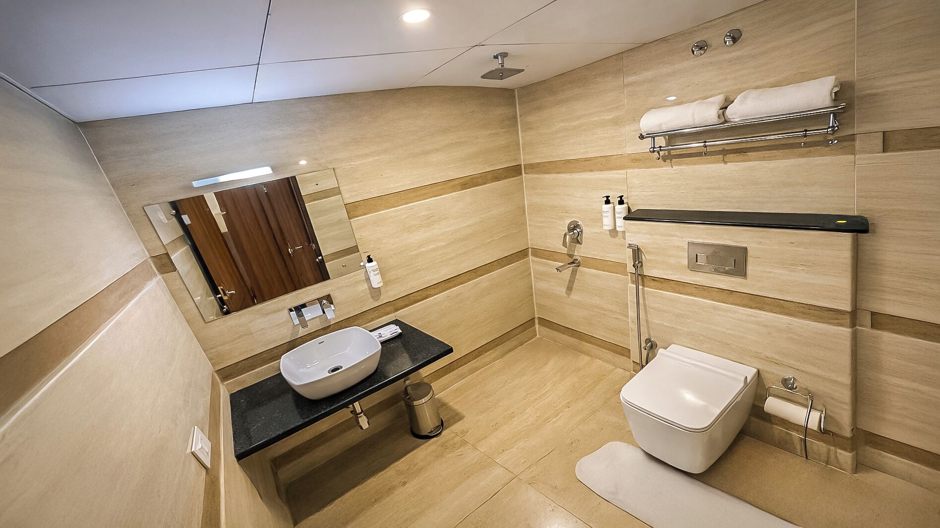 Un baño moderno con un espejo grande, un lavabo, un inodoro y una ducha.
