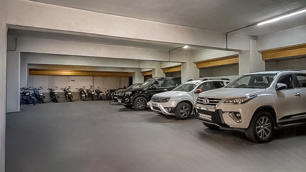 A parking garage with multiple rows of parked cars and motorcycles.