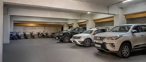 A parking garage with multiple rows of parked cars and motorcycles.